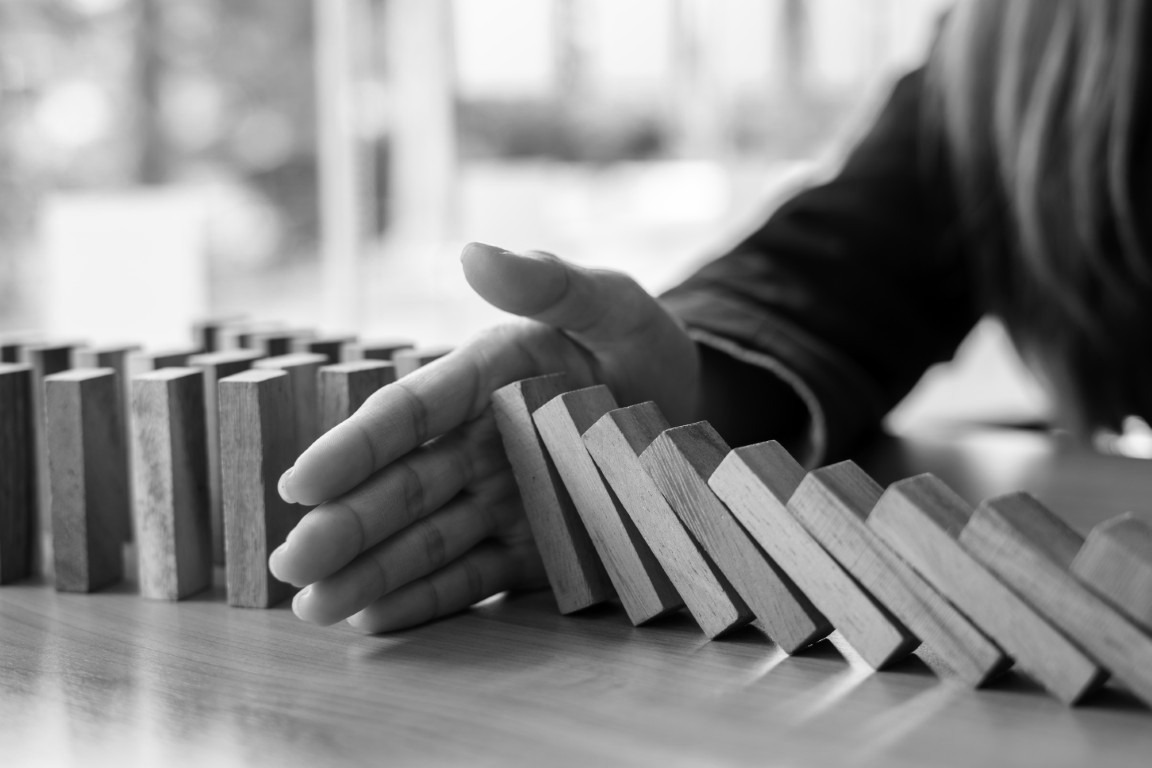 Row of falling dominoes is stopped by a hand